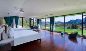 a bedroom with a large white bed and large windows at Zhangjiajie Cloudscape Lodge-English Services-Near the Ticket Gate in Zhangjiajie