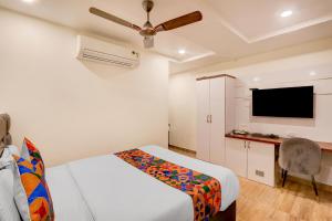 a bedroom with a bed and a flat screen tv at FabHotel Radha Rani Residency in Khammam