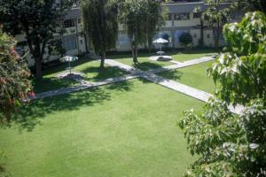 a green yard with umbrellas in front of a building at Stylish Studio Retreat- Inside Kunste Hotel in Nakuru +5 photos