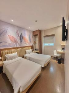 a hotel room with two beds and a tv at Alltrue Lite Hotel Nagoya Hill Batam in Nagoya