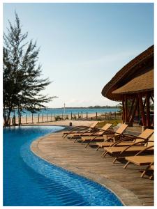 a swimming pool with lounge chairs and the beach at Tanoma Sumba in Maujawa