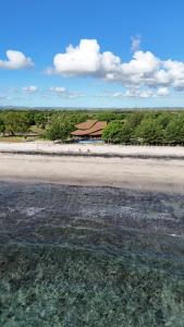 a beach with a building in the background and water at Tanoma Sumba in Maujawa