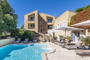 a pool with chairs and umbrellas next to a building at Le Major in Cadenet