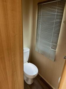 a bathroom with a white toilet and a window at Caravan by the Sea 641 in Kinmel Bay