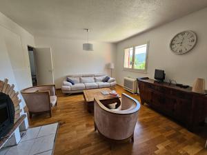 a living room with a couch and a clock on the wall at Maison 5 chambres à Dieulefit in Dieulefit