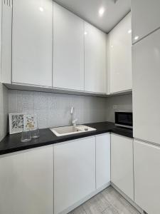 Una cocina blanca con gabinetes blancos y un fregadero. en Wilanów Residence - Two-Room Apartment, en Varsovia 13 fotos más