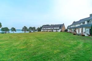 a large yard with houses and the water in the background at Ciel Etoilé - Proche de la mer in Locmariaquer