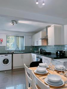 Una cocina con una mesa con platos y copas de vino. en Modern 3 Bed house with parking - Chorley near M61, en Heapey
