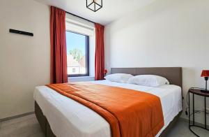 a bedroom with a bed with an orange blanket on it at Appartement Porte Bonheur in Rochefort