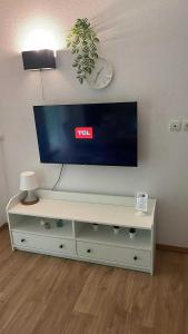 TV de pantalla plana en la parte superior de un centro de entretenimiento blanco en Les Charmes C40B - Le Val Joly, en Eppe-Sauvage