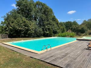 a large swimming pool with a wooden deck next to at Gîtes OSTAL de Marcillac avec piscine - Le Pigeonnier in Capelou