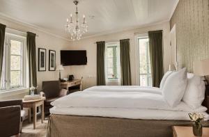 a bedroom with a large white bed and a chandelier at Fru Haugans Hotel in Mosjøen