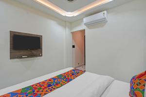 a room with a bed and a tv on a wall at FabHotel Aurika Retreat in Indore