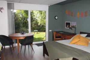 a bedroom with a bed and a table and a window at B&B Even Heukelom - Kamer met Tuin in Afferden