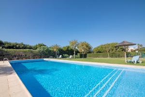 a blue swimming pool with an umbrella next to a yard at Do Vale Hollidays in Galé