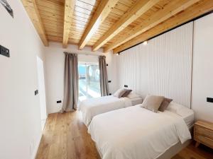 two beds in a room with white walls and wooden ceilings at Chalet Cueva del Sol in Tahiche +76 photos