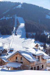 a ski lodge in the snow with a ski slope at Almdorf Hohentauern by ALPS RESORTS in Hohentauern