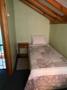 a small bedroom with a bed and a table at Cabañas Casa Blanca in Valdivia