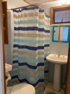 a bathroom with a shower curtain and a sink at Cabañas Casa Blanca in Valdivia