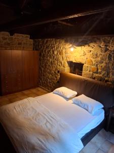 a bedroom with a large bed in a stone wall at Panos Stone House in Lílaia