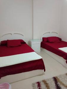 two beds with red and white sheets in a bedroom at شقه على البحر مباشره فى عمارات الظباط مصطفى كامل سيتي اسكوير in Alexandria