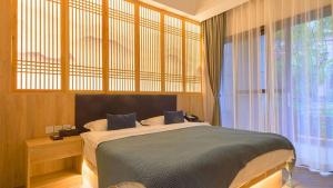a bedroom with a bed and a large window at Heinemanns Guest House With Jacuzzi Local Family vibes in Baoguosi