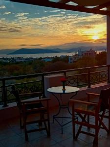 a balcony with a table and chairs and a sunset at The house of joy in Egina