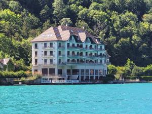 a large house on the shore of a body of water at Le Studio Rivage - Surplombant le lac in Duingt