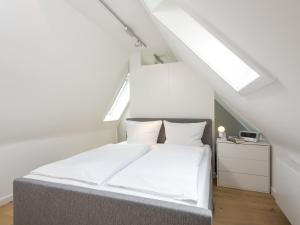 Un dormitorio con una cama con sábanas blancas y una ventana. en K14 von Appartements & Mehr, en Kampen