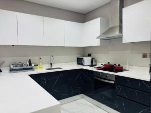 a kitchen with white cabinets and black appliances at Breathtaking Sea Views& Balcony Luxurious Stay in Manama