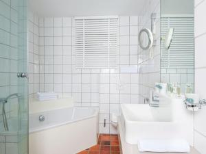 a white bathroom with a tub and a sink at Käpt'n Cook 4 von Appartements & Mehr in Kampen +1 photo