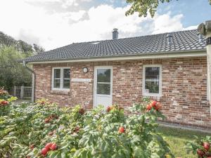 a brick house with a garden in front of it at Moderne Doppelhaushälfte - perfekt zu zweit in Dagebüll