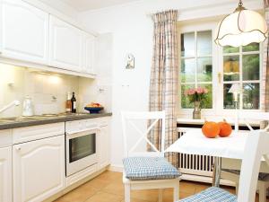 a kitchen with white cabinets and a table with oranges on it at Enenhoog Flugente von Appartements & Mehr in Kampen