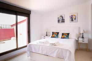una camera da letto bianca con un letto bianco e una finestra di Ático con vistas a Port Saplaya