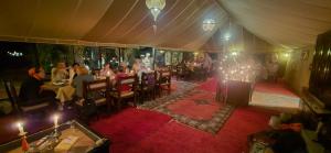 un groupe de personnes assises à des tables dans une pièce dans l'établissement Salam Luxury Camp, à Merzouga