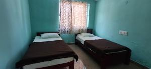 two beds in a room with blue walls and a window at B Pool Villa in Yercaud