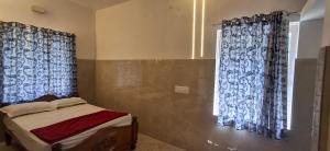a bedroom with a bed and two windows with curtains at B Pool Villa in Yercaud