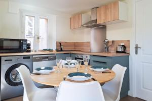 eine Küche mit einem Holztisch und Stühlen sowie eine Küche mit einer Waschmaschine in der Unterkunft Cozy 1BR in the heart of the old village of Villeneuve-Loubet - BENAKEY in Villeneuve-Loubet + 5 Fotos