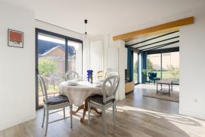 ein weißes Esszimmer mit Tisch und Stühlen in der Unterkunft Le Relais d'Ezy - 3 chambres in Ézy-sur-Eure