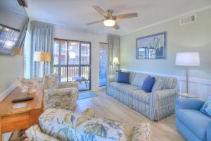 a living room with a blue couch and chairs at Tilghman Beach & Racquet Club - 114 in Myrtle Beach