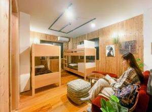 a woman sitting on a couch in a room with bunk beds at Kaido Yuzawa Onsen Hostel in Yuzawa +37 photos