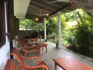 a patio with wooden tables and chairs and trees at Kadol Villa in Unawatuna