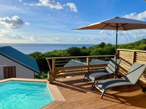 a deck with two chairs and an umbrella and a pool at Caribbean Shelter in Bouillante
