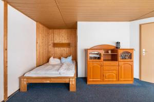 a bedroom with a bed and a wooden cabinet at Bungalow 21 - Kimbucht in Reichendorf