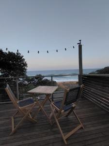 a picnic table and two chairs on a deck with the beach at uMkhaKhaya Container Home in Westbrook