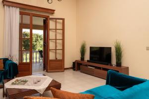 a living room with a tv and a blue couch at Selini Suite 2nd floor Panoramic Vineyard Views in Kallithea