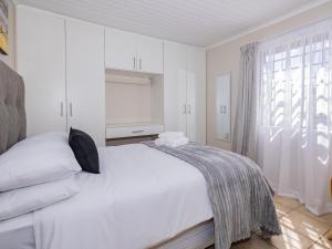 a white bedroom with a bed and a window at Urban Oaks in Bellville