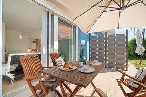 a wooden table with chairs and an umbrella on a patio at Residence Blumar Jesolo Golf Club in Lido di Jesolo