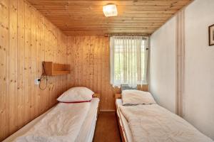 two beds in a room with wooden walls at Bungalow 29 - Kimbucht in Reichendorf