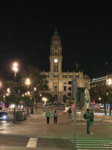 a large building with a clock tower at night at Burnay Porto Suites in Porto